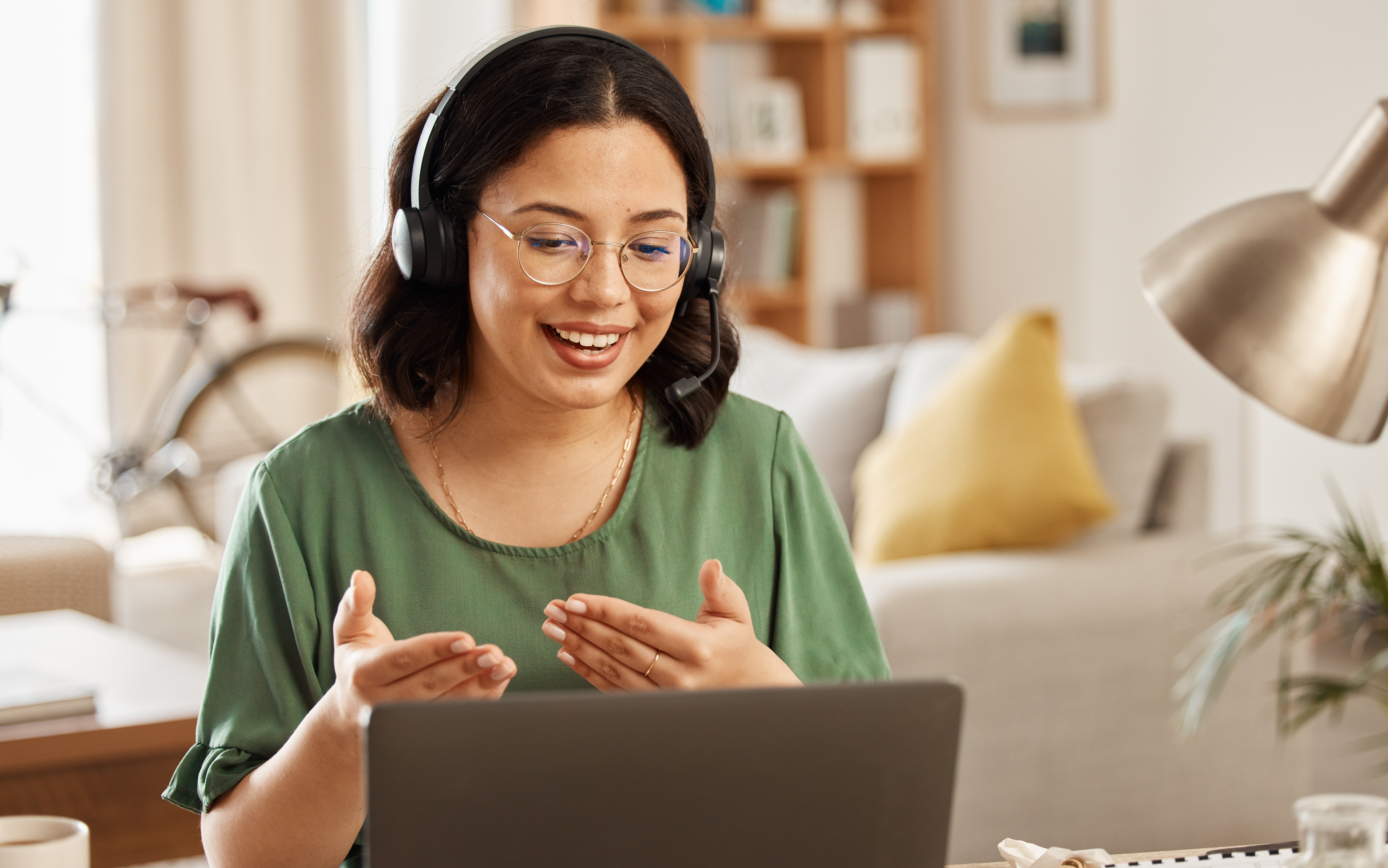 Woman with headset sitting in front of a laptop and taking part in a video call