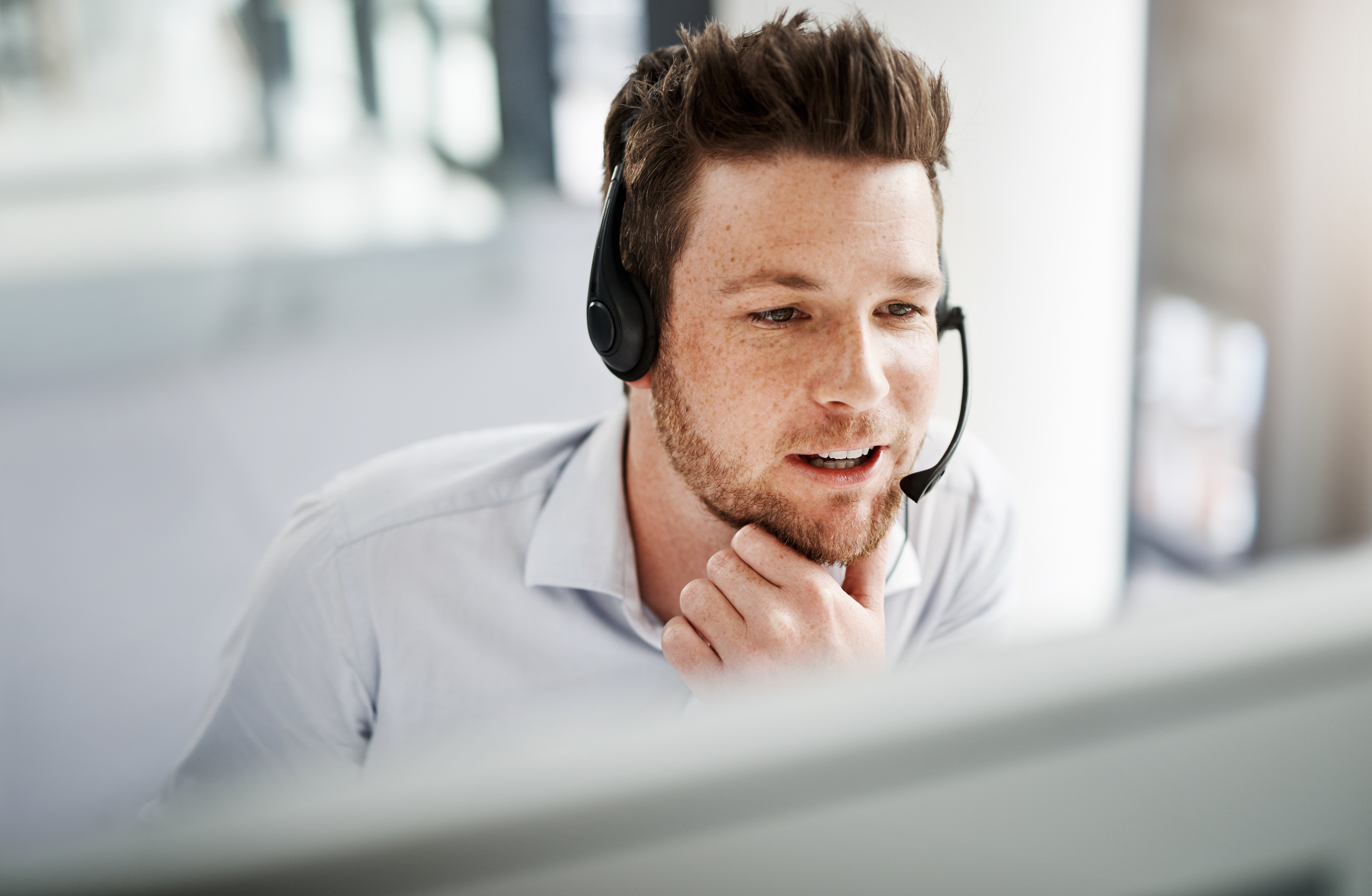 Support employee with headset sitting in front of a screen